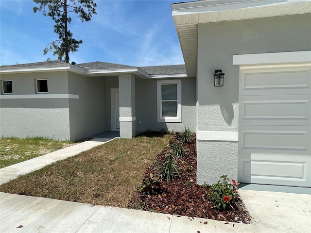 property entrance with stucco siding and roof with shingles