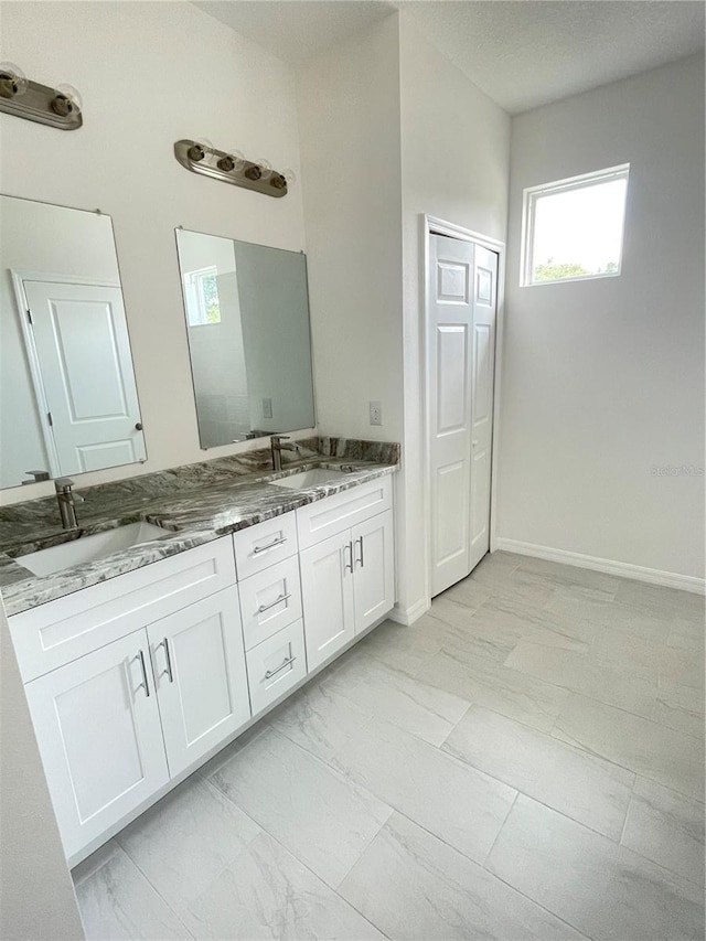 bathroom with double vanity, marble finish floor, and a sink