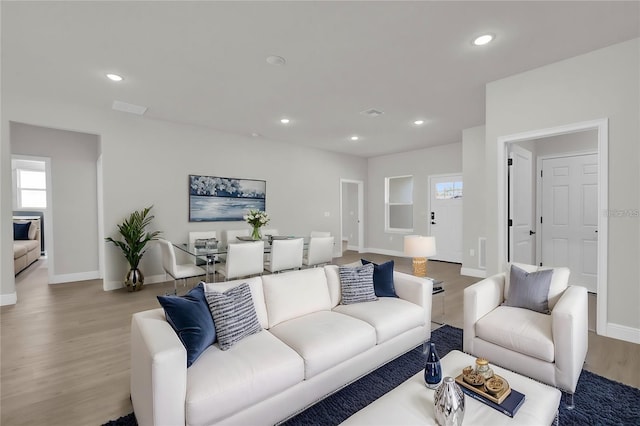 living room with a wealth of natural light, light wood-style floors, and baseboards