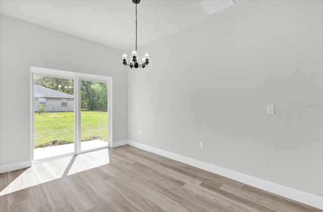 unfurnished room with visible vents, light wood-style flooring, a notable chandelier, and baseboards