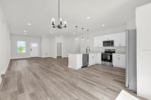 kitchen with open floor plan, a peninsula, visible vents, appliances with stainless steel finishes, and a sink