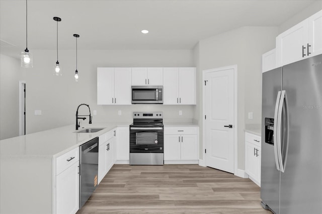 kitchen featuring a peninsula, light countertops, appliances with stainless steel finishes, light wood finished floors, and a sink