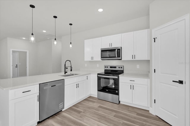 kitchen with a sink, a peninsula, white cabinetry, recessed lighting, and stainless steel appliances