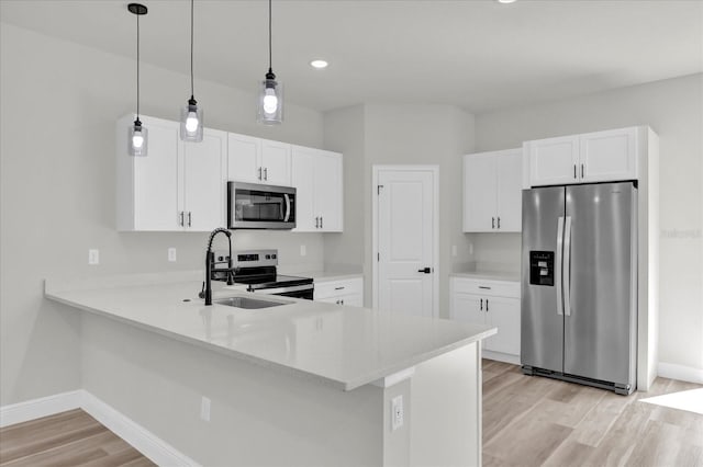 kitchen with a sink, light countertops, a peninsula, light wood-style floors, and stainless steel appliances