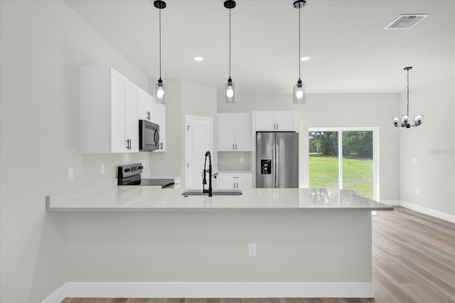 kitchen featuring a peninsula, light countertops, a sink, stainless steel appliances, and baseboards
