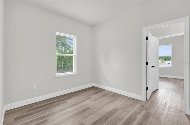 spare room featuring a wealth of natural light, light wood-type flooring, and baseboards