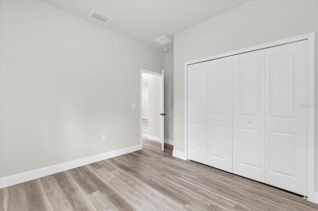 unfurnished bedroom featuring visible vents, a closet, light wood-style flooring, and baseboards