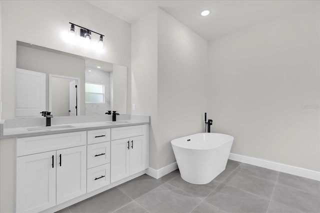 full bathroom with a sink, baseboards, double vanity, and a freestanding tub