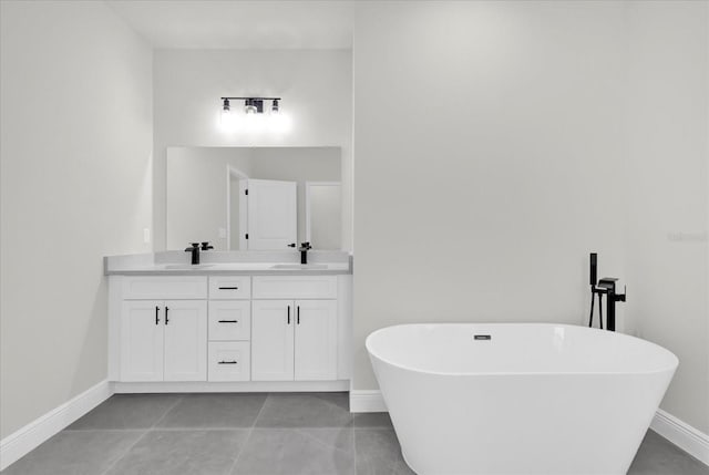 full bathroom featuring a freestanding bath, double vanity, baseboards, and a sink