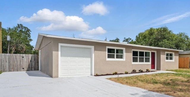 ranch-style home with stucco siding, an attached garage, concrete driveway, and fence