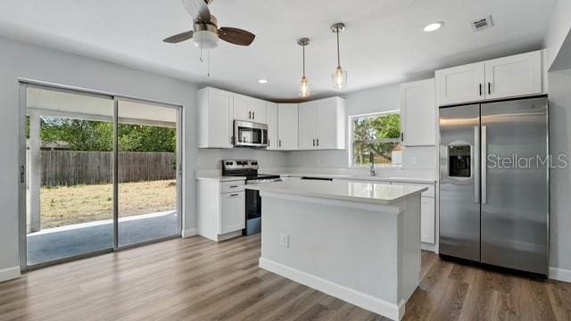 kitchen featuring white cabinets, stainless steel appliances, a sink, wood finished floors, and light countertops