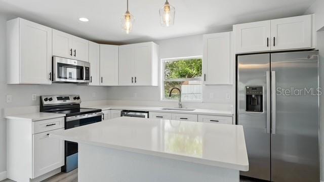 kitchen featuring a kitchen island, appliances with stainless steel finishes, white cabinetry, and a sink