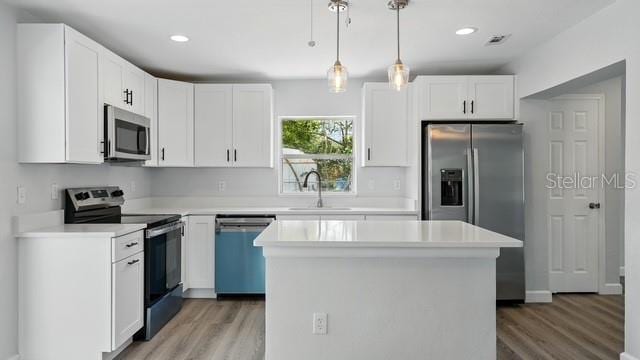 kitchen featuring white cabinetry, stainless steel appliances, light wood finished floors, and a sink
