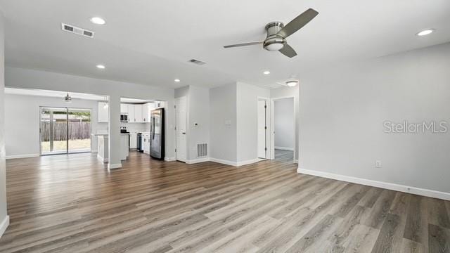 unfurnished living room with wood finished floors, visible vents, baseboards, and ceiling fan