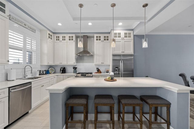 kitchen featuring a tray ceiling, tasteful backsplash, wall chimney exhaust hood, and appliances with stainless steel finishes
