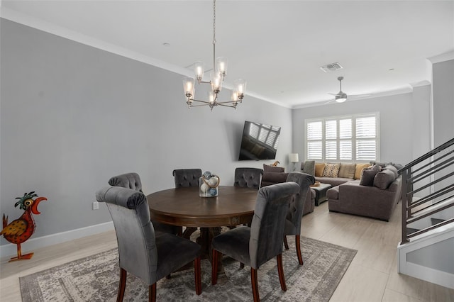 dining area with ceiling fan with notable chandelier, baseboards, ornamental molding, and visible vents
