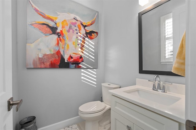 half bathroom featuring vanity, baseboards, and toilet
