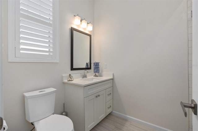 bathroom featuring toilet, wood finished floors, vanity, and baseboards
