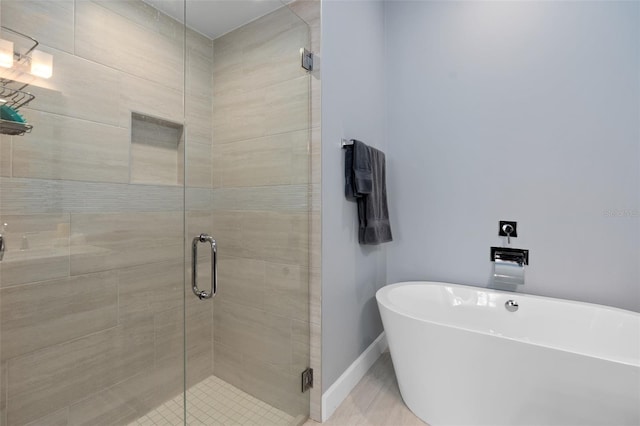 bathroom with baseboards, a freestanding tub, and a stall shower