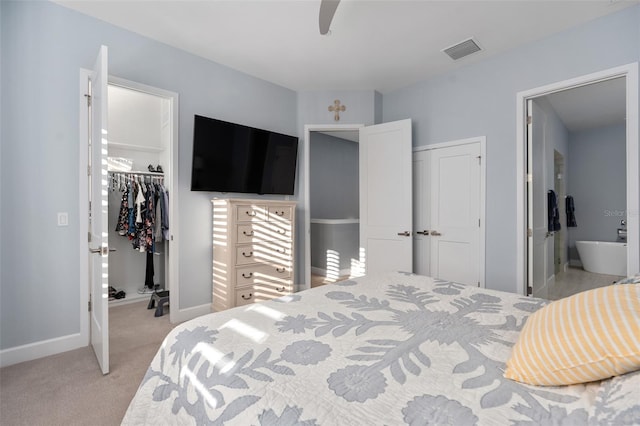 bedroom featuring connected bathroom, a closet, light colored carpet, a spacious closet, and visible vents