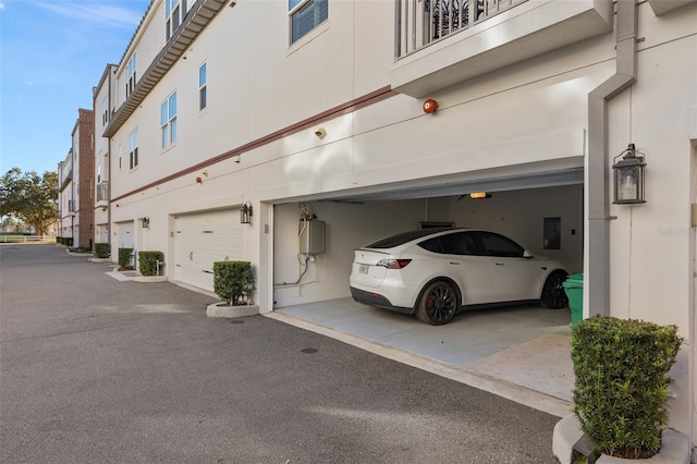 exterior space featuring water heater, a garage, and aphalt driveway