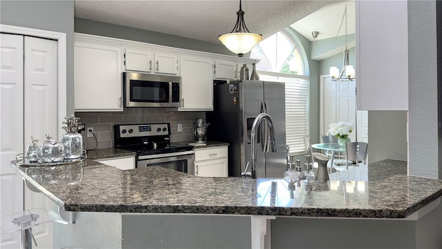 kitchen featuring stainless steel appliances, tasteful backsplash, a peninsula, and white cabinets