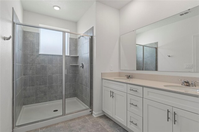 bathroom featuring double vanity, visible vents, a sink, and a stall shower