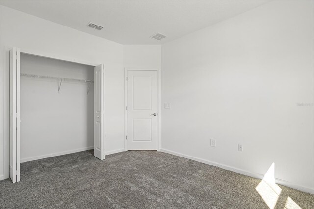 unfurnished bedroom featuring visible vents, baseboards, a closet, and carpet