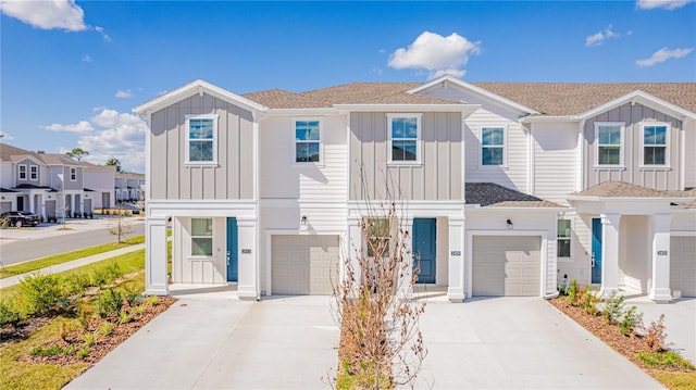 townhome / multi-family property featuring a shingled roof, a garage, board and batten siding, a residential view, and driveway