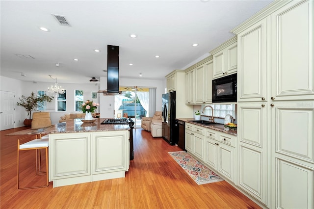 kitchen featuring open floor plan, cream cabinets, black appliances, visible vents, and a sink