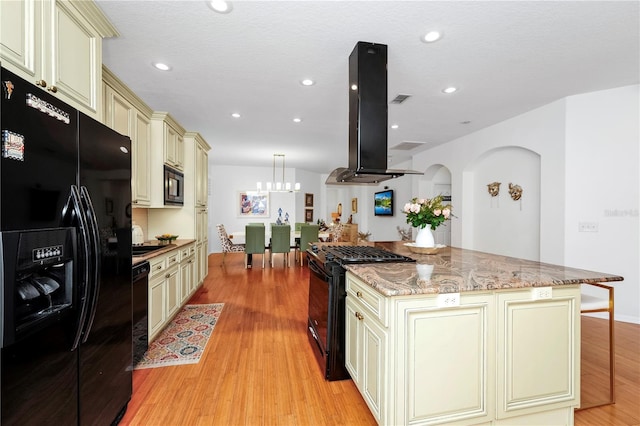 kitchen with black appliances, light wood-style flooring, island exhaust hood, and cream cabinets