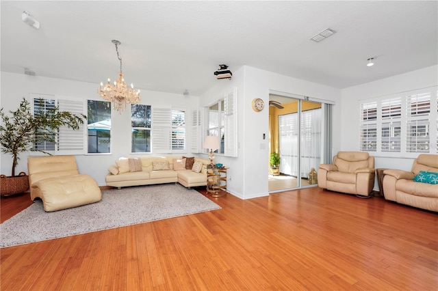 living room featuring a chandelier, visible vents, baseboards, and wood finished floors