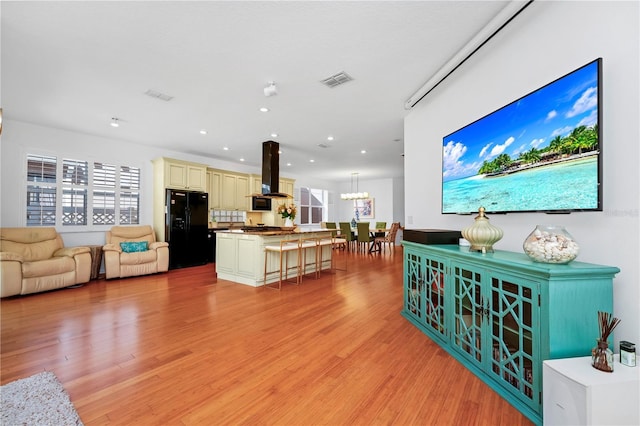 living room featuring a chandelier, light wood-style floors, visible vents, and recessed lighting