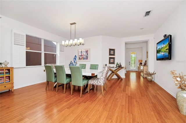 dining space with baseboards, light wood-type flooring, a notable chandelier, and visible vents