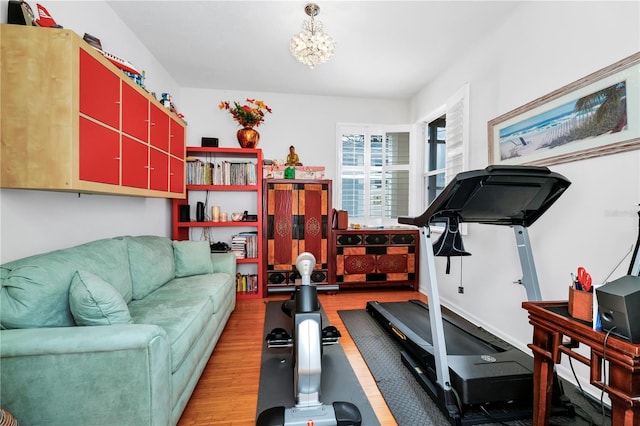 workout area featuring a notable chandelier and wood finished floors