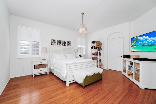bedroom featuring a notable chandelier, light wood-style flooring, and baseboards