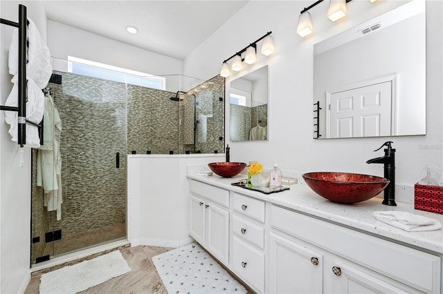 full bath featuring a shower stall, double vanity, visible vents, and a sink