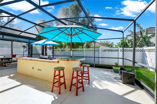 view of patio with a lanai, outdoor dry bar, and fence