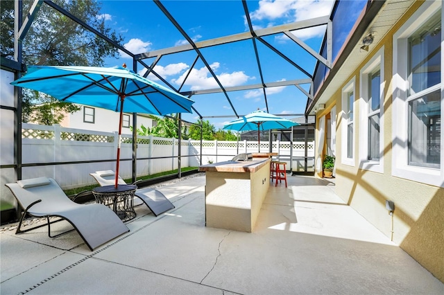view of patio / terrace featuring a lanai, an outdoor kitchen, outdoor dry bar, and fence