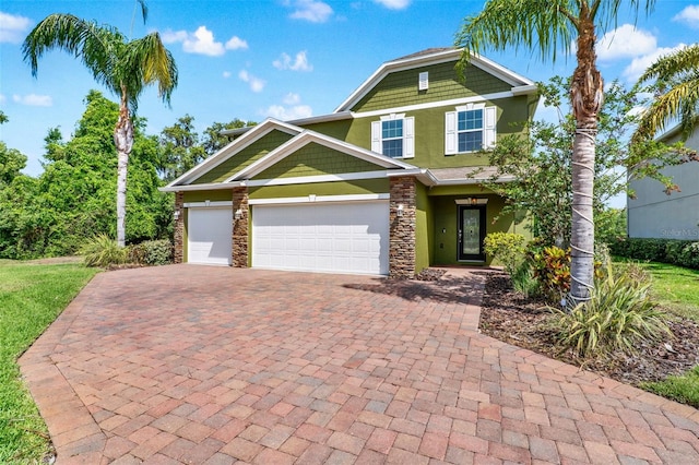 view of front of house featuring stucco siding, a garage, stone siding, and decorative driveway