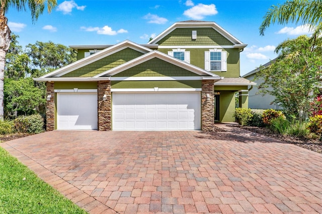 craftsman inspired home featuring stone siding, stucco siding, a garage, and decorative driveway