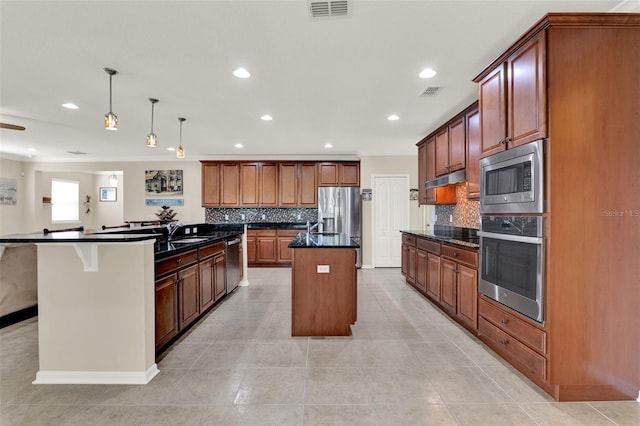 kitchen featuring backsplash, visible vents, appliances with stainless steel finishes, and a kitchen island with sink