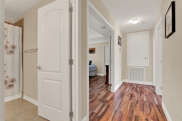hall with baseboards, ornamental molding, wood finished floors, and visible vents