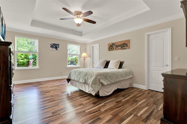 bedroom featuring a ceiling fan, wood finished floors, a raised ceiling, baseboards, and ornamental molding