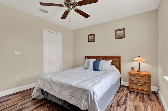 bedroom with wood finished floors, visible vents, a ceiling fan, and baseboards