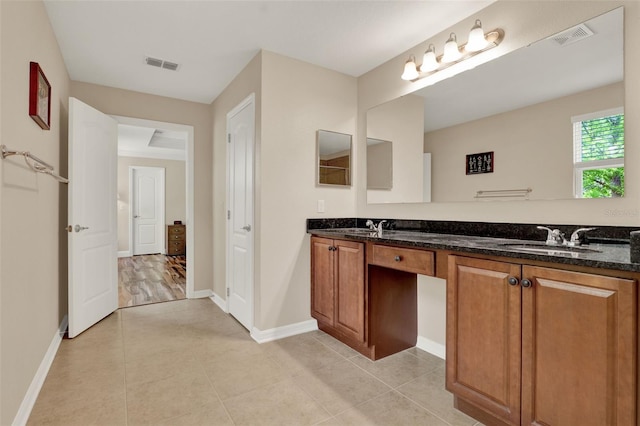 bathroom with tile patterned floors, a sink, double vanity, baseboards, and visible vents