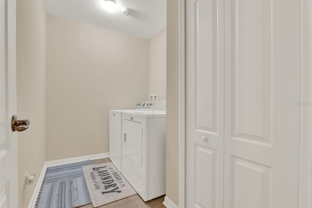 clothes washing area featuring baseboards, washer and clothes dryer, and laundry area