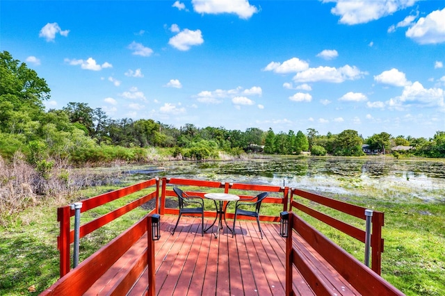 wooden terrace featuring outdoor dining area and a water view