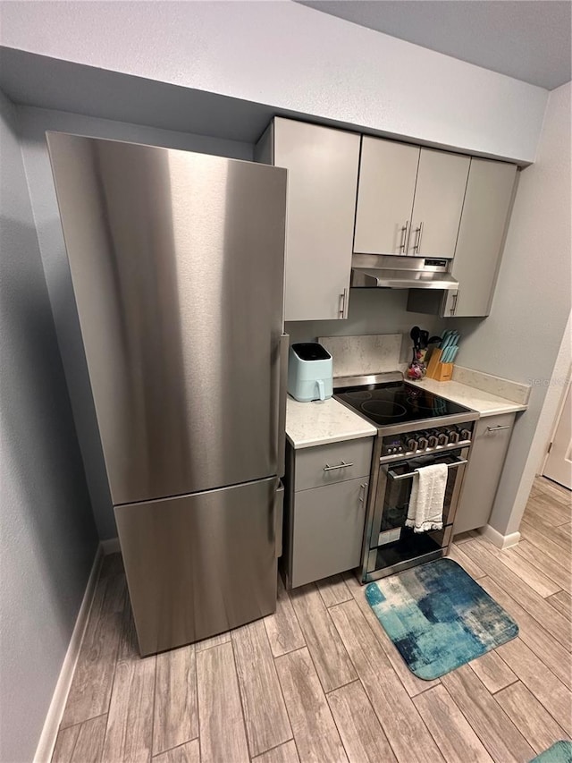 4800 S Semoran Blvd Unit 101, Orlando, FL 32822 - kitchen featuring gray cabinets, light wood-type flooring, appliances with stainless steel finishes, and under cabinet range hood