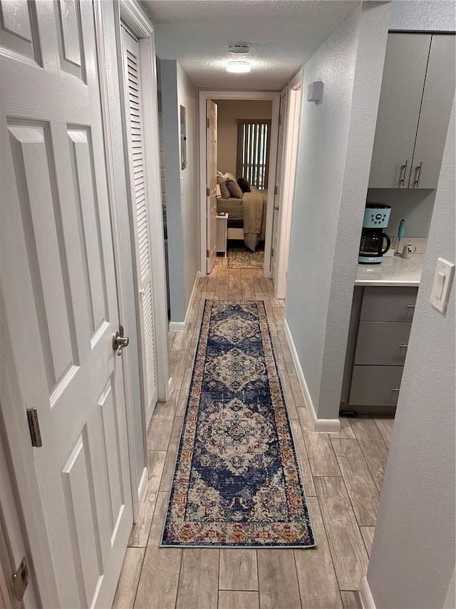 4800 S Semoran Blvd Unit 101, Orlando, FL 32822 - hall featuring light wood-type flooring, a textured ceiling, and baseboards